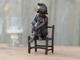 Figura de bronce. Niña en silla. 16 x 9 x 7 cm.