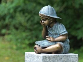 Figura de bronce. Niño leyendo. 29 x 24 x 25 cm.